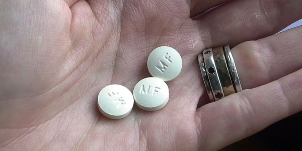 FFROA – Abortion Pill Close-up of a hand holding three white pills marked MF, representing abortion medication.
