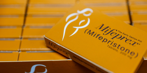 A box of Mifeprex (mifepristone) tablets labeled as the early option pill, shown among a stack of identical packages.